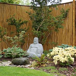 Ein Granitbuddha leistet Gesellschaft im Garten