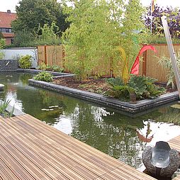 Bali-Garten mit großer Wasserfläche und Holzterrasse